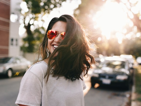 Woman smiling walking on a street in sunglasses