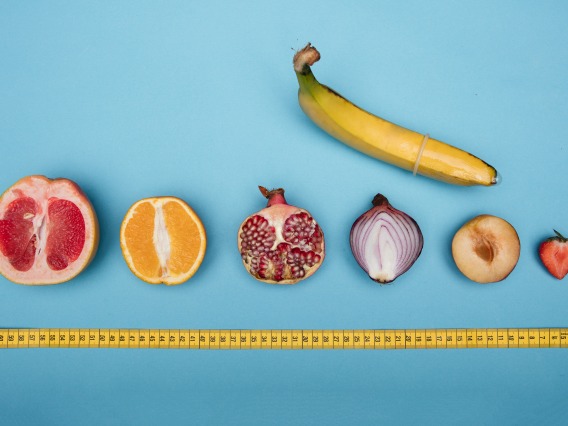 Bananna with cross section of grapefruit, organge, onion, strawberry lined up with a tape measure underneath