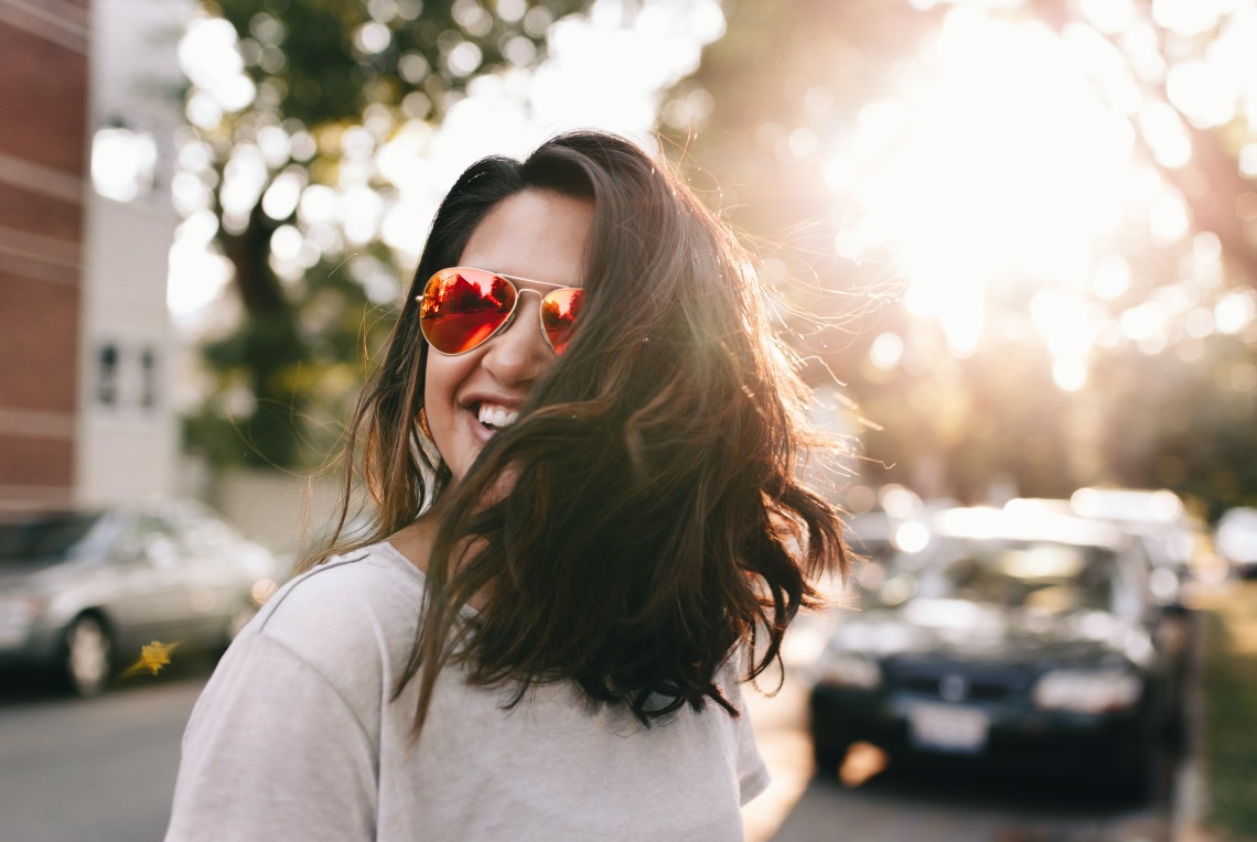 Woman smiling walking on a street in sunglasses