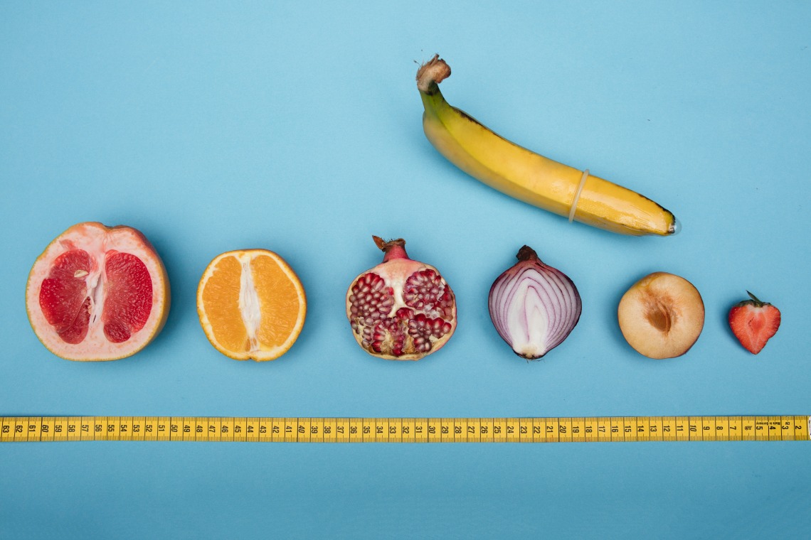 Bananna with cross section of grapefruit, organge, onion, strawberry lined up with a tape measure underneath